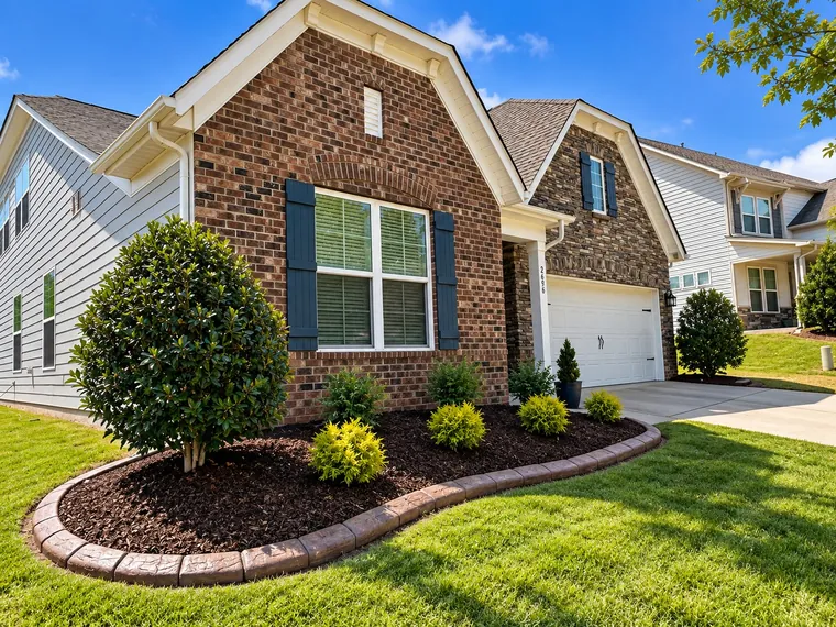 Brick house with an oval mulched bed, evergreens and a poured curb