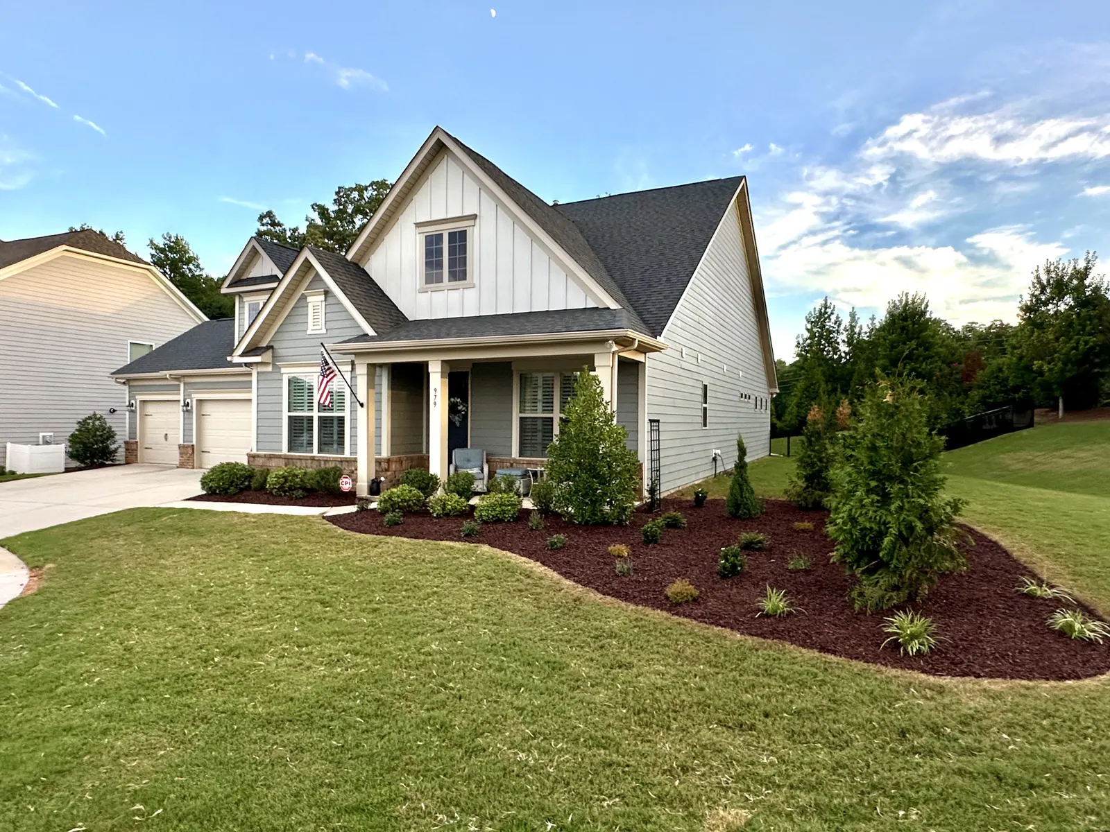 A finished Fort Mill front yard with a curved mulch bed, evergreens and a green lawn