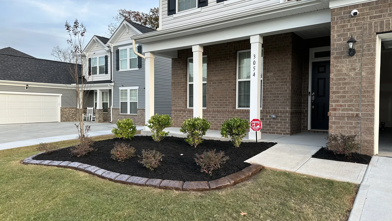 A new-construction front bed with a poured curb, mulch and young shrubs
