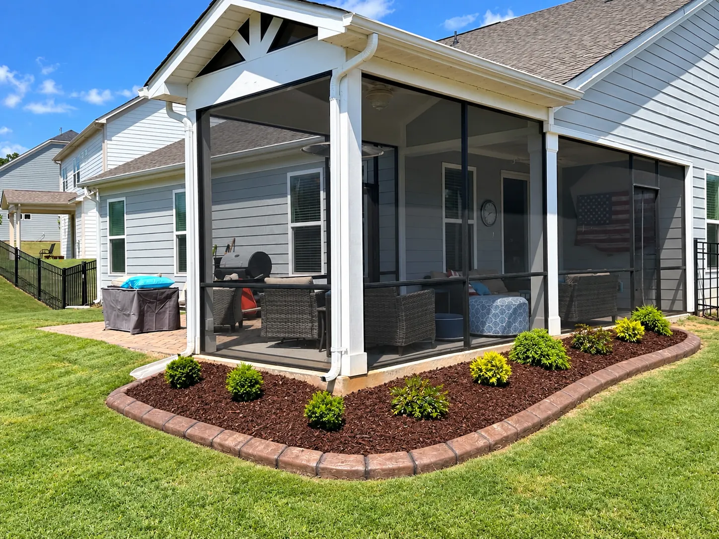 A poured curb and mulched shrubs wrapping a screened porch